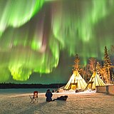 Nächtliche Winterlandschaft im Norden Kanadas, über der Polarlichter zu sehen sind.
