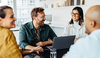 Führungskraft und Kolleg*innen sitzen gemeinsam am Tisch.