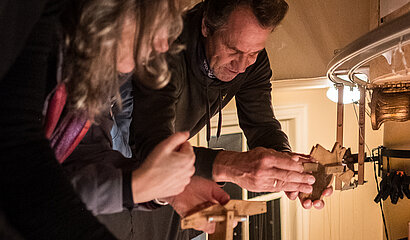 Mehrere Menschen sind über eine Brüstung gebeugt und halten jeweils ein Steuerkreuz