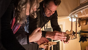 Mehrere Menschen sind über eine Brüstung gebeugt und halten jeweils ein Steuerkreuz