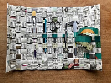 Werkzeugrolle aus geflochtenem Zeitungspapier mit Fächern für Pinsel, Stifte, Schere und Lineal.