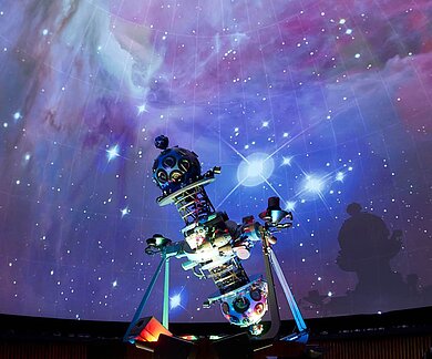 Die Aliens Felix, grün mit Antenne auf dem Kopf und Luna, rosa mit lila Strubbelhaaren im Vordergrund, im Hintergrund Ausschnitte der Sonne und der Planeten unseres Sonnensystems (animiert).

