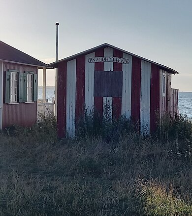 Rot-weiß gestrichene Holzhütte am Strand.