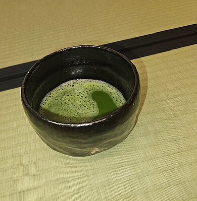 eine Tasse Tee mit Untertasse. Die Tasse hat eine Bemalung mit japanischen Frauen