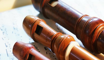 zwei Sopran- und eine Altblockflöte liegen auf einem Blatt Noten