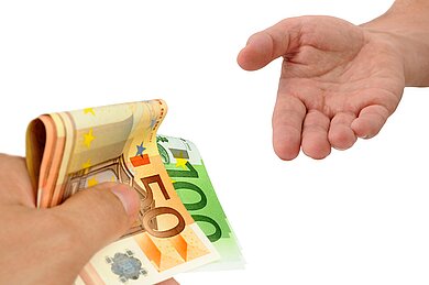 Eine Person gibt einer anderen Person Bargeld in die Hand