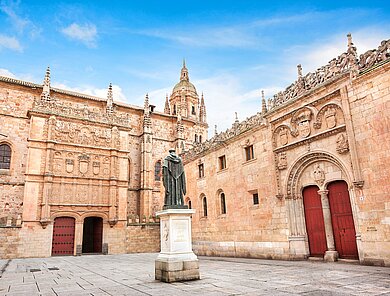 Innenhof mit roten Holzportalen und Statue der Universität von Salamanca, Spanien.
