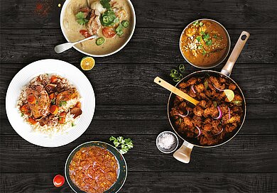 Spezialitäten aus Zentralafrika Auf einem Tisch stehen verschiedene Teller. Darauf finden sich unterschiedlich zubereitete Geflügel- und Hähnchengerichte, welche bunt garniert wurden.