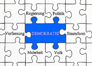Puzzleteile mit Herzstück Demokratie in der Mitte