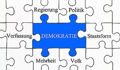 Puzzleteile mit Herzstück Demokratie in der Mitte