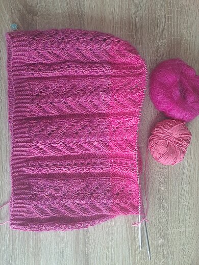 Ein rosafarbenes Strickprojekt mit verschiedenen Mustern und passender Wolle.