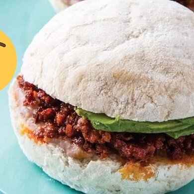 Pambazos Veracruzanos Ein burgerartiges Gericht, mit Avocados, liegt auf einem hellblauen großen Teller.