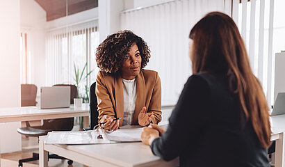 Zwei Frauen sitzen sich im Büro gegenüber für ein Mitarbeitergespräch..