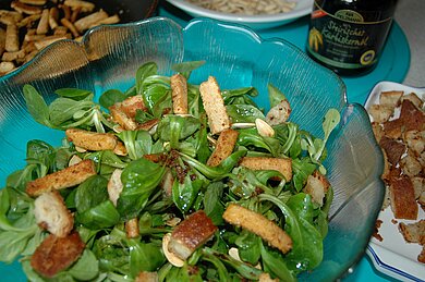 Vegane Vielfalt International In einer großen Glasschüssel ist ein badischer Feldsalat angemacht und wir gerade serviert.