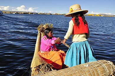 Zwei peruanische Frauen stehen auf einem Schilfboot im Titicaca-See.