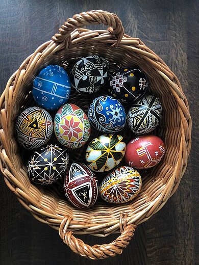 Korb mit mehreren bunten Eiern, die mit geometrischen Formen bemalt sind. 