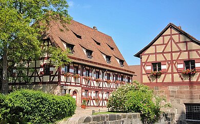 altes Fachwerkhaus, historisch restauriert mit blühenden Blumen an den Fensterläden.