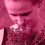 Portrait einer jungen Frau, die an einer Pflanze riecht