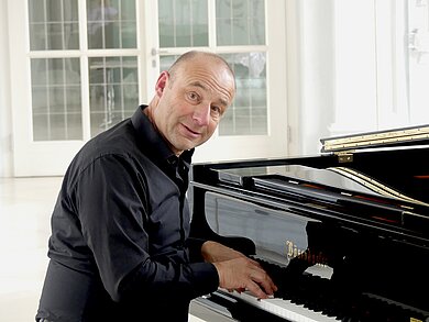 Der Künstler Stefan Rieger sitzt am Flügel.