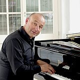 Der Künstler Stefan Rieger sitzt am Flügel.