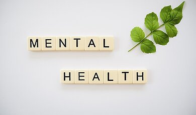 Stress goodbye! Mental Health hello! Mit Scrabble Steinen ist das Wort Mental health gelegt.