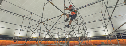 Arbeiter klettert an einem Gerüst hoch. 