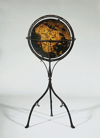 Historischer Globus auf einem dreibeinigen Metallgestell mit goldfarbenen und schwarzen Landmassen