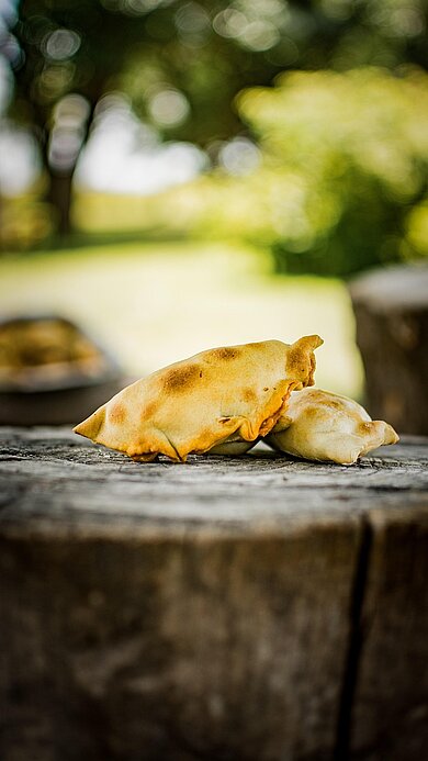 Mehrere Teigtaschen werden von einer Person in den Händen gehalten.