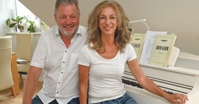 Mann und Frau vor einem Klavier.